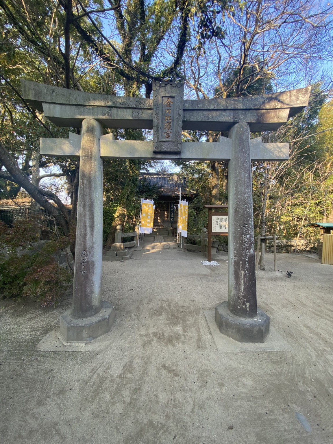 木々に囲まれた、金刀比羅宮の額がかかる石の鳥居