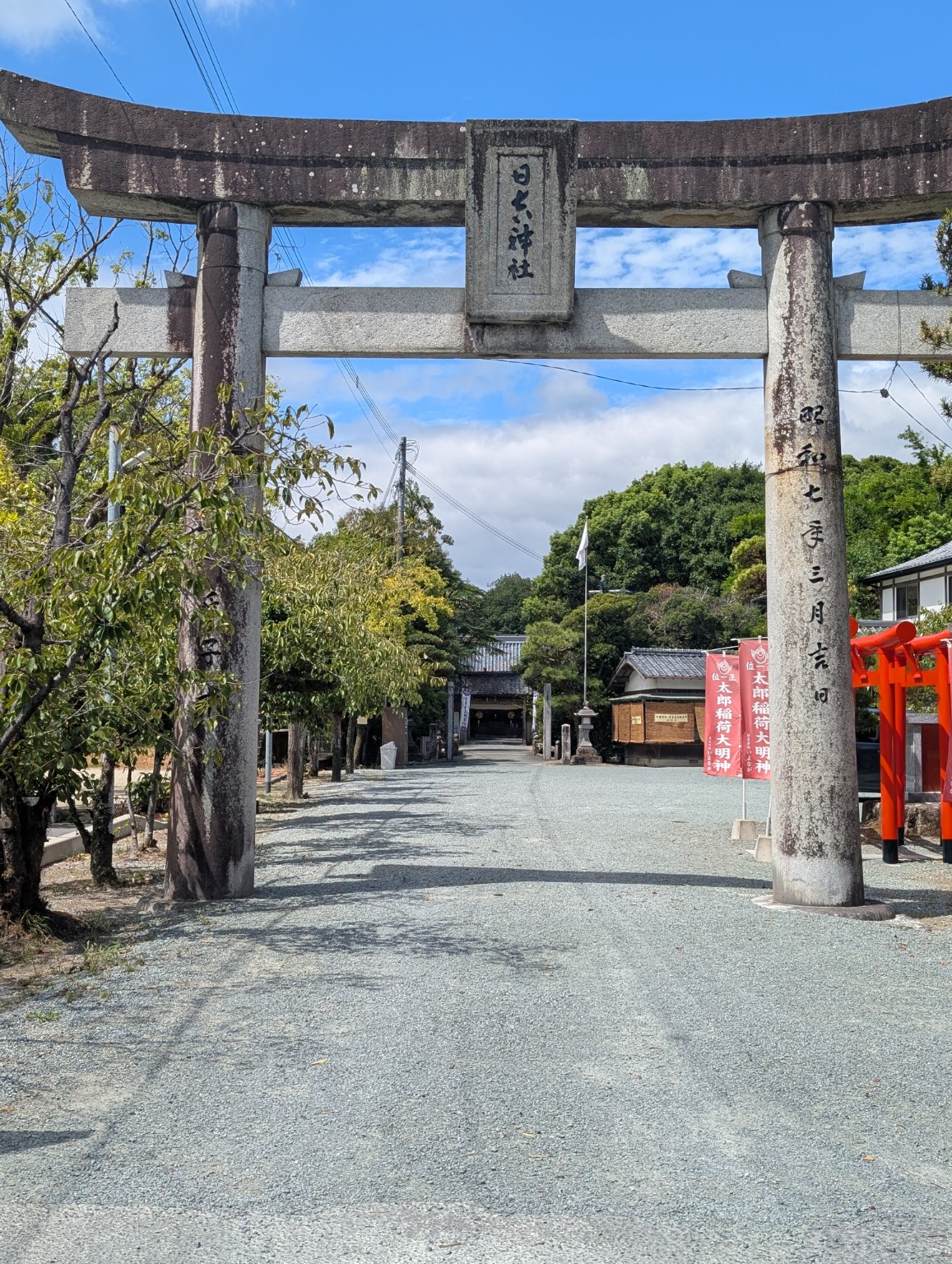 青空の下、日吉神社の額がかかる石鳥居から境内を望む